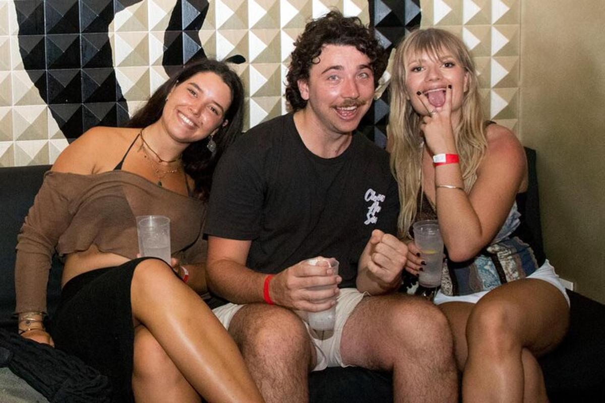 skupina tří lidí sedících na gauči s drinky