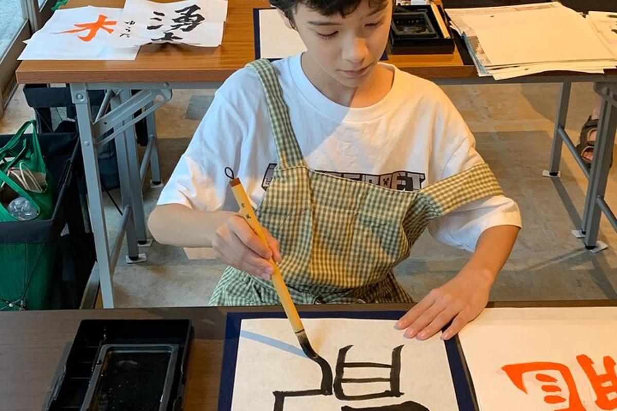 un noi jove amb davantal treballant en una pintura