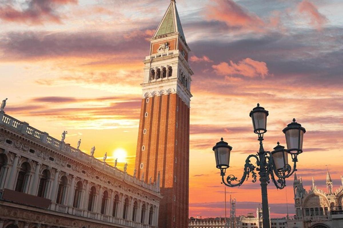 Una alta torre de reloj con una puesta de sol al fondo