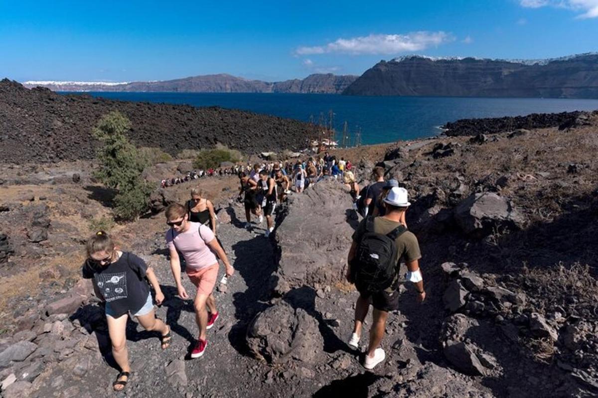um grande grupo de pessoas caminhando em uma trilha rochosa
