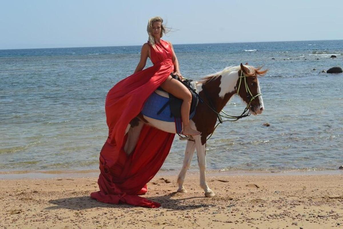 una donna in abito a cavallo sulla spiaggia
