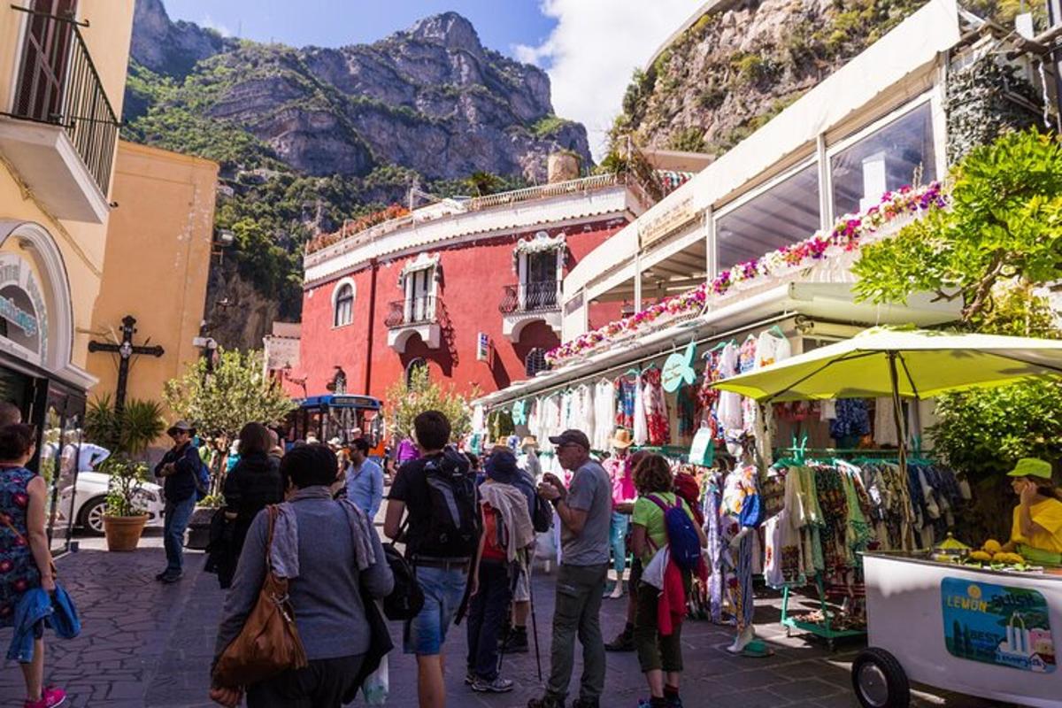 a crowd of people walking through a market with mountains in the background