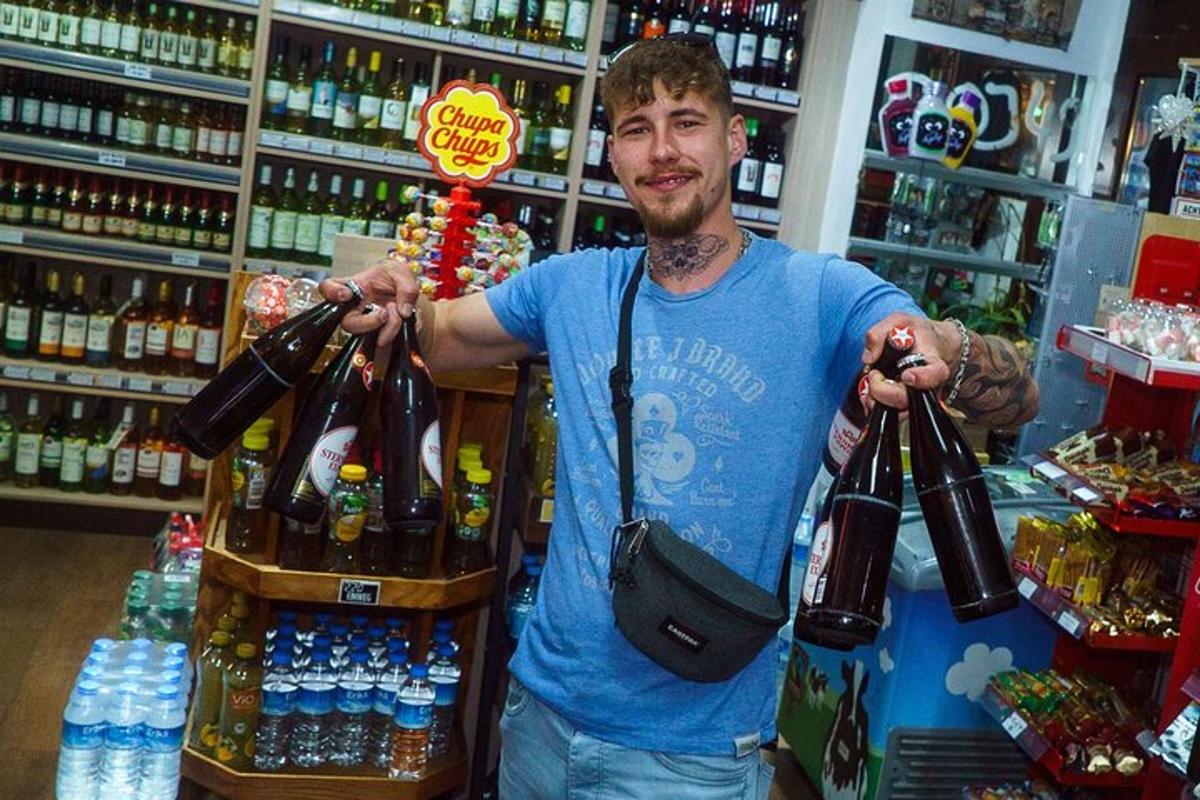 seorang lelaki berdiri di kedai memegang sekumpulan botol
