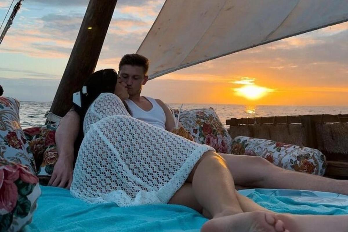 muž a žena sedící na lodi a pozorující západ slunce