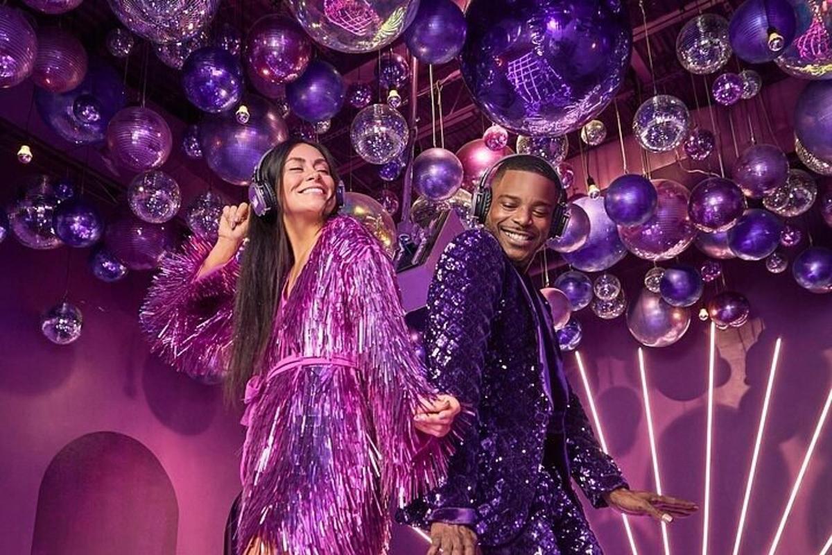 a man and a woman standing on a stage with purple balloons