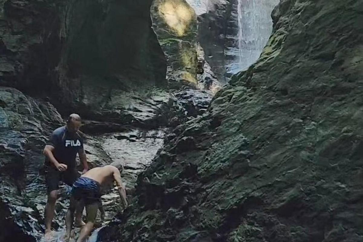 dua orang berdiri di hadapan air terjun