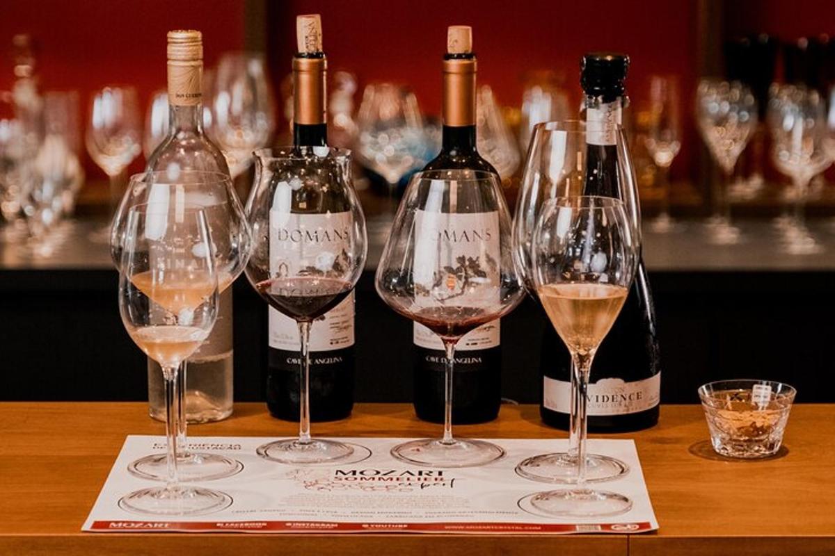 four wine glasses sitting on a table with wine bottles
