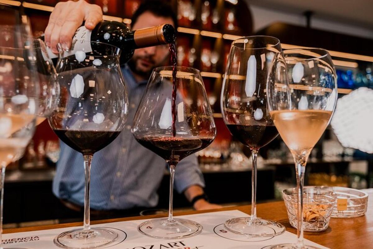 a person pouring wine into four wine glasses