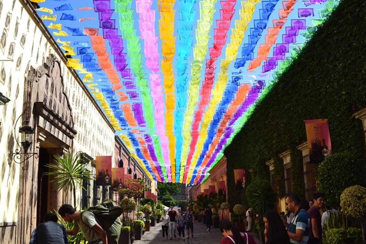 Un grupo de personas caminando por una calle bajo un techo colorido.