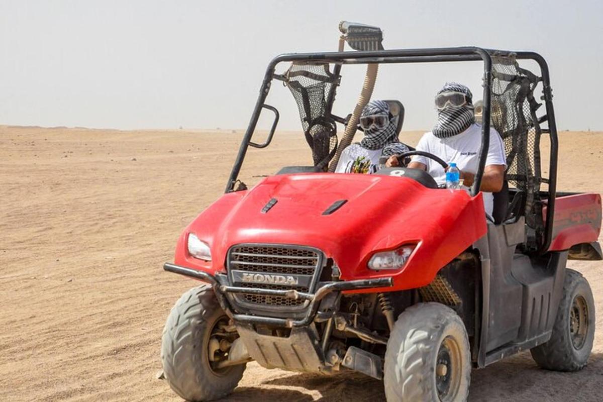 two people driving a red atv in the desert