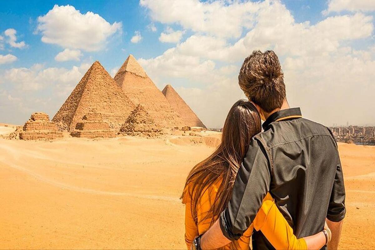 Un hombre y una mujer de pie frente a las pirámides.