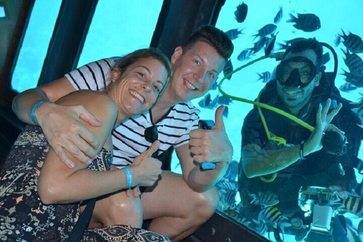 een man en een vrouw die duimen omhoog steken voor een aquarium