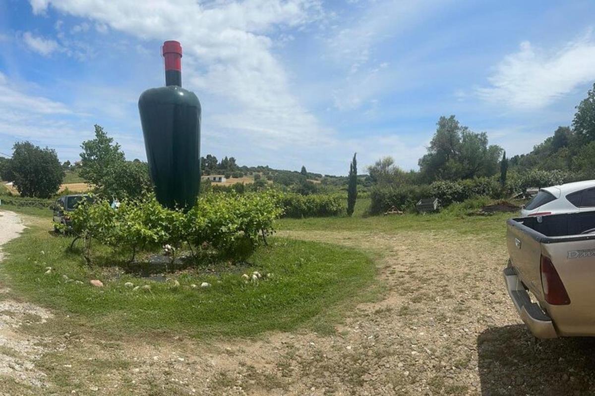 ένα αυτοκίνητο παρκαρισμένο σε ένα χωράφι με ένα γιγάντιο μπουκάλι κρασιού