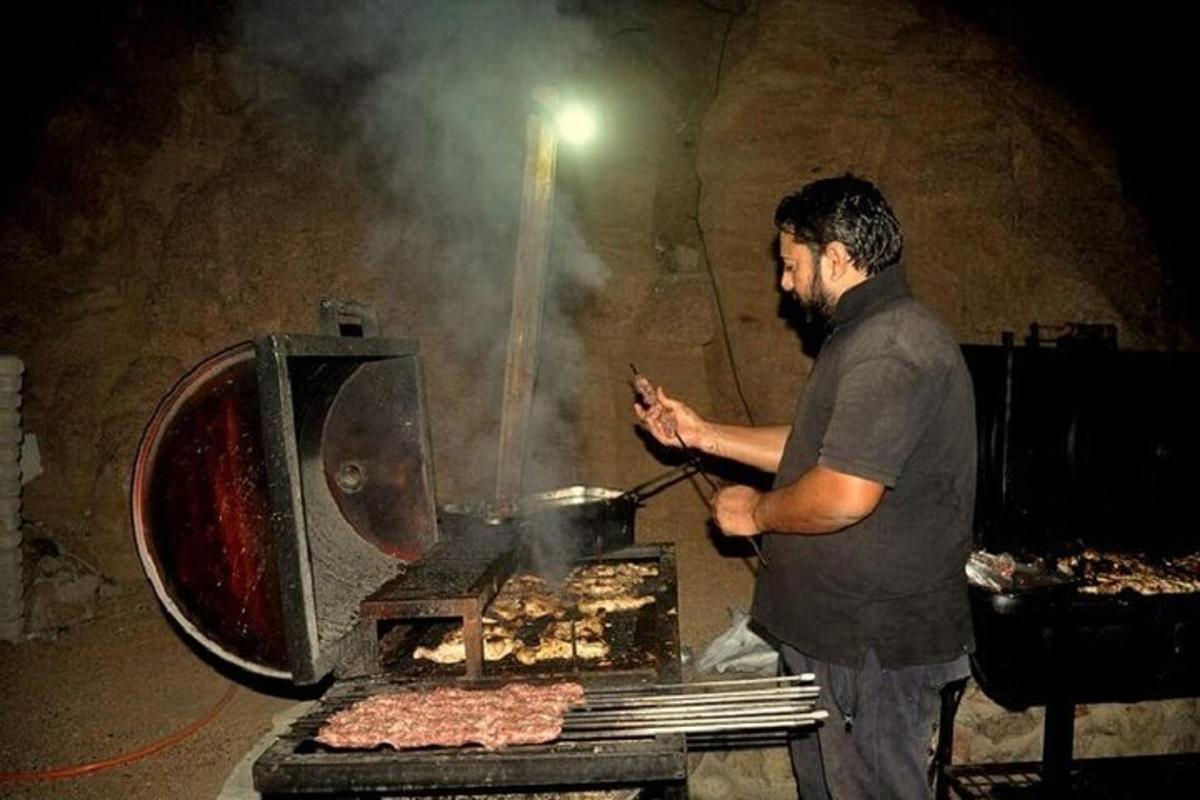 seorang lelaki sedang memasak daging di atas panggangan