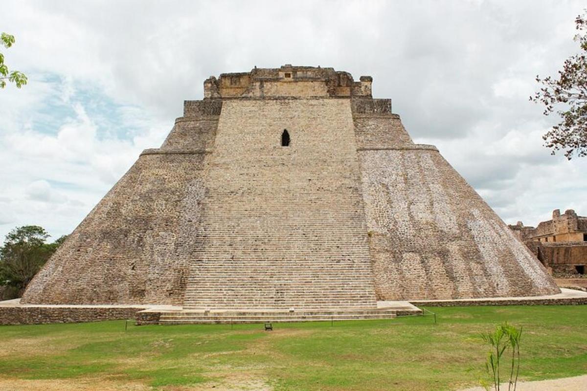 a large pyramid building with a grass field in front