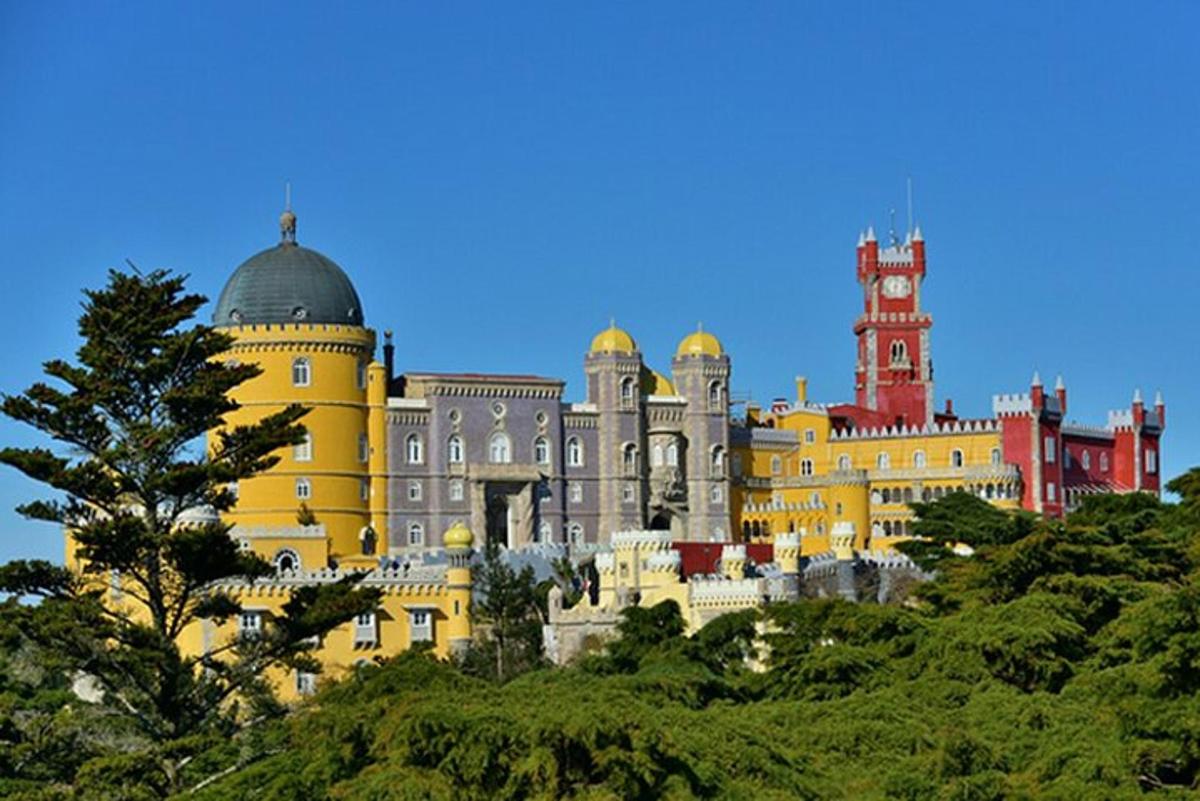 um grande edifício amarelo com uma torre de relógio em uma colina