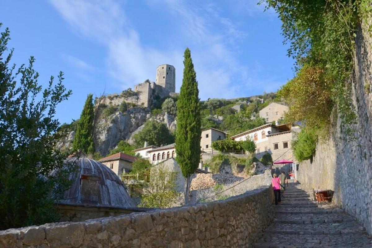 una dona baixant unes escales de pedra amb un castell al turó