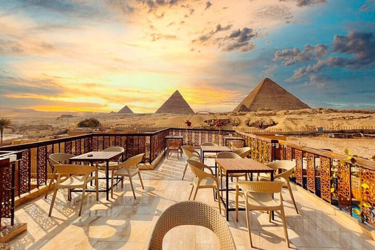 balkon se stoly a židlemi s výhledem na pyramidy
