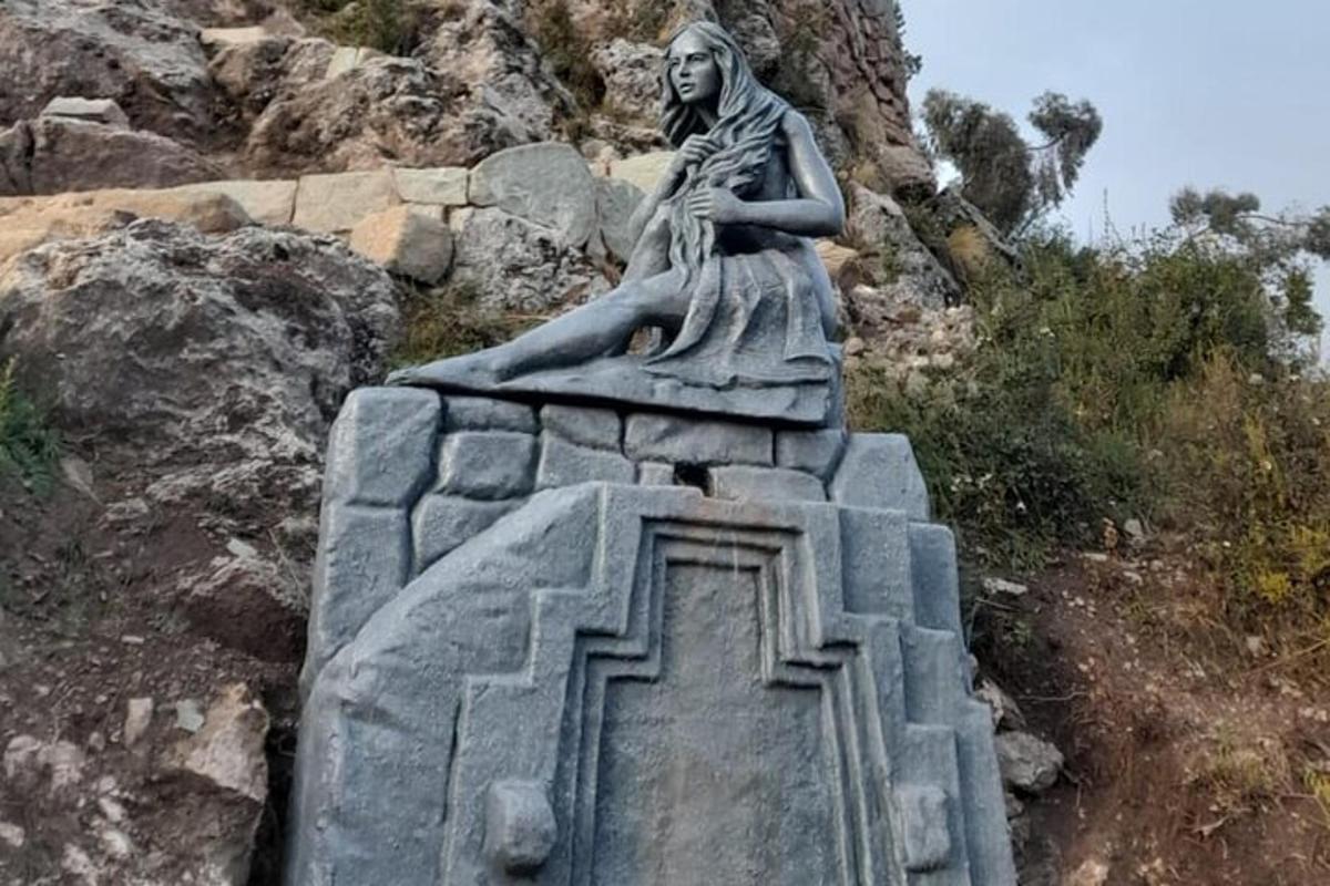 en statue av en kvinne som sitter på en stein
