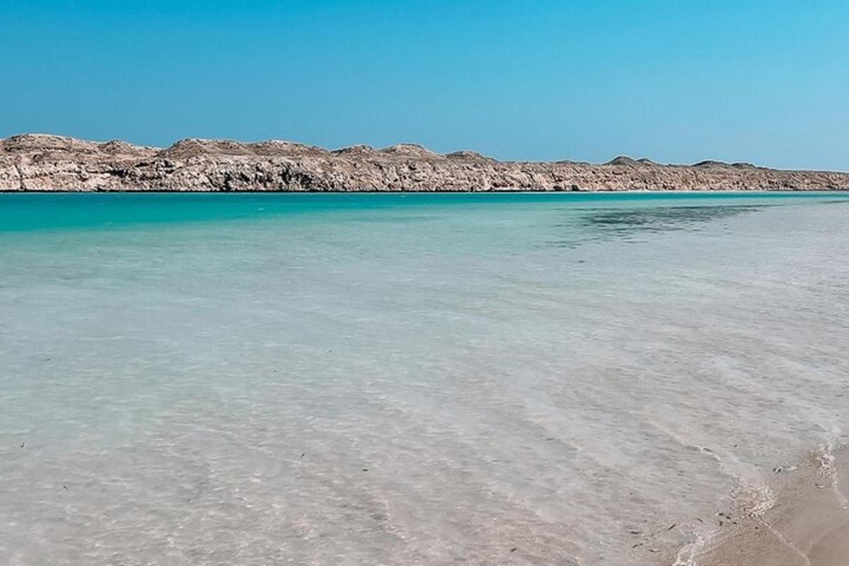 una spiaggia con acqua limpida e rocce sullo sfondo