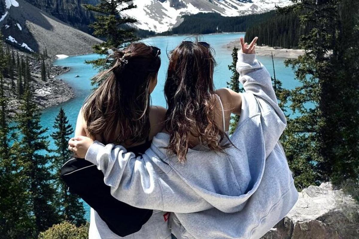 two women standing on a mountain looking at a lake