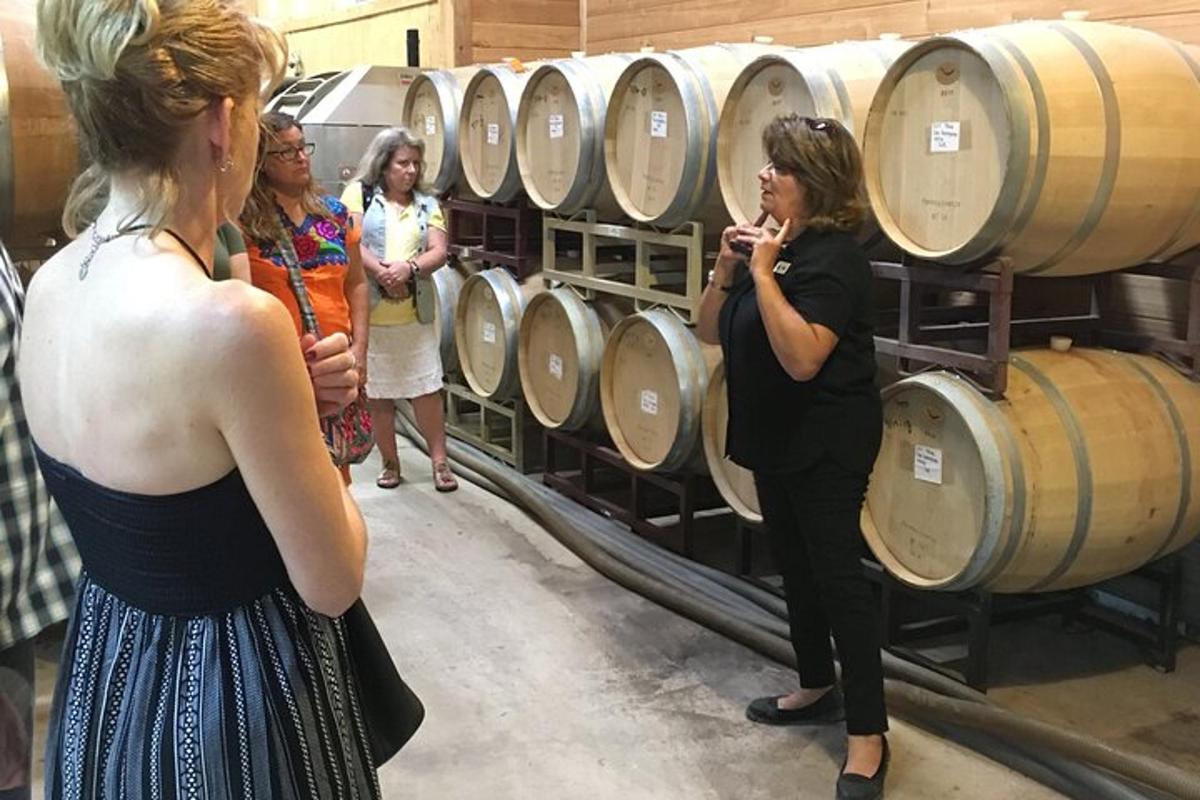 a group of women standing next to a bunch of wine barrels