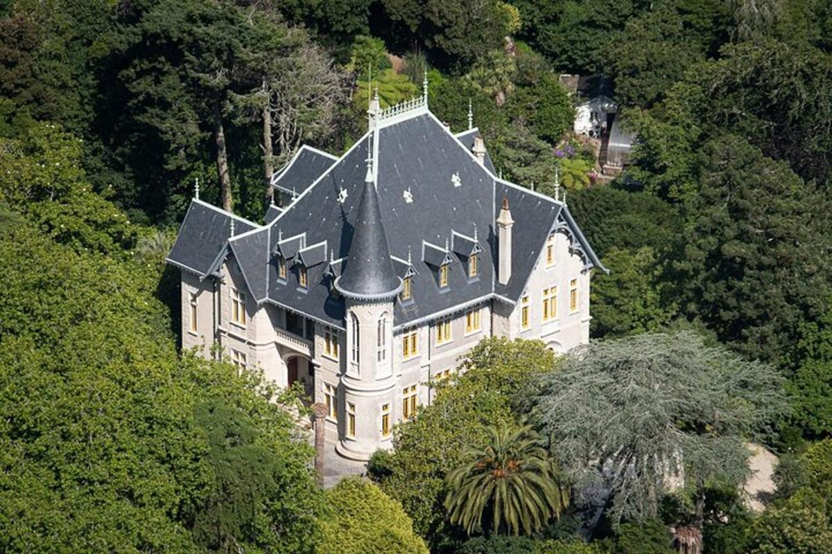 uma grande casa branca com um telhado preto em uma colina