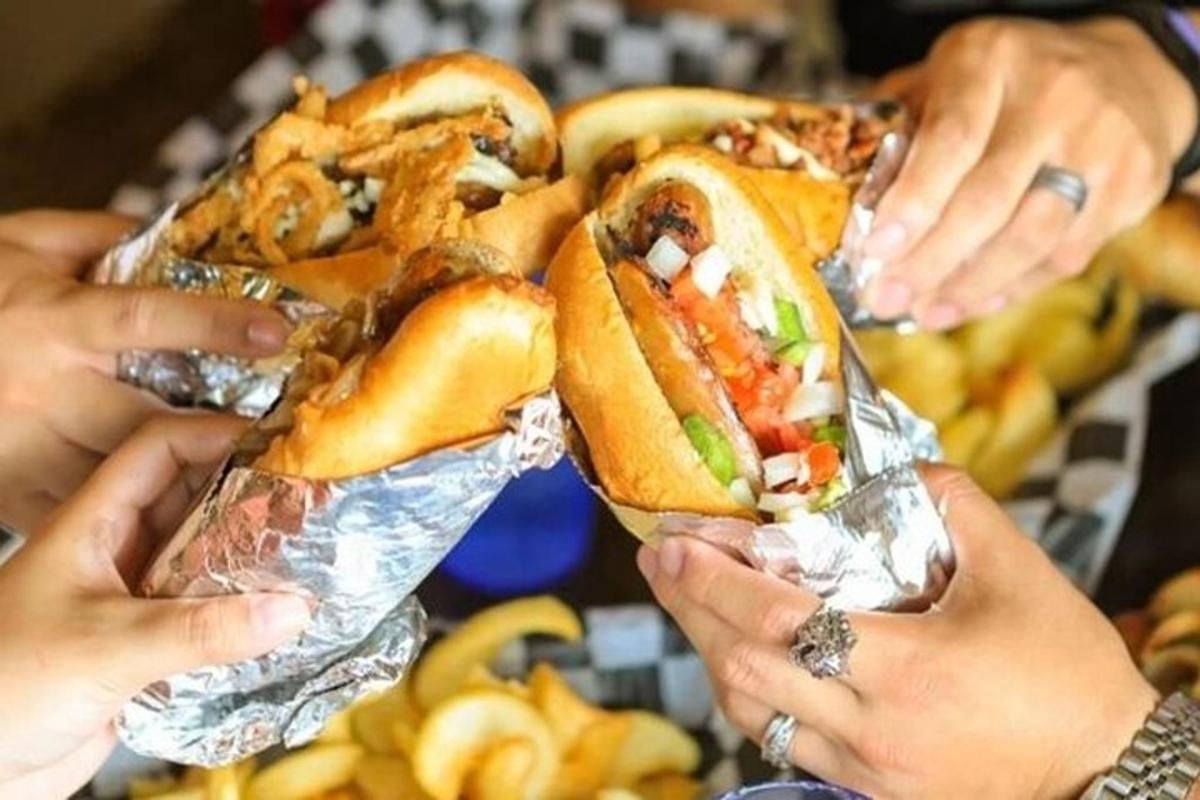 egy csoport ember tartja a kezében hot dogokat és sült krumplit
