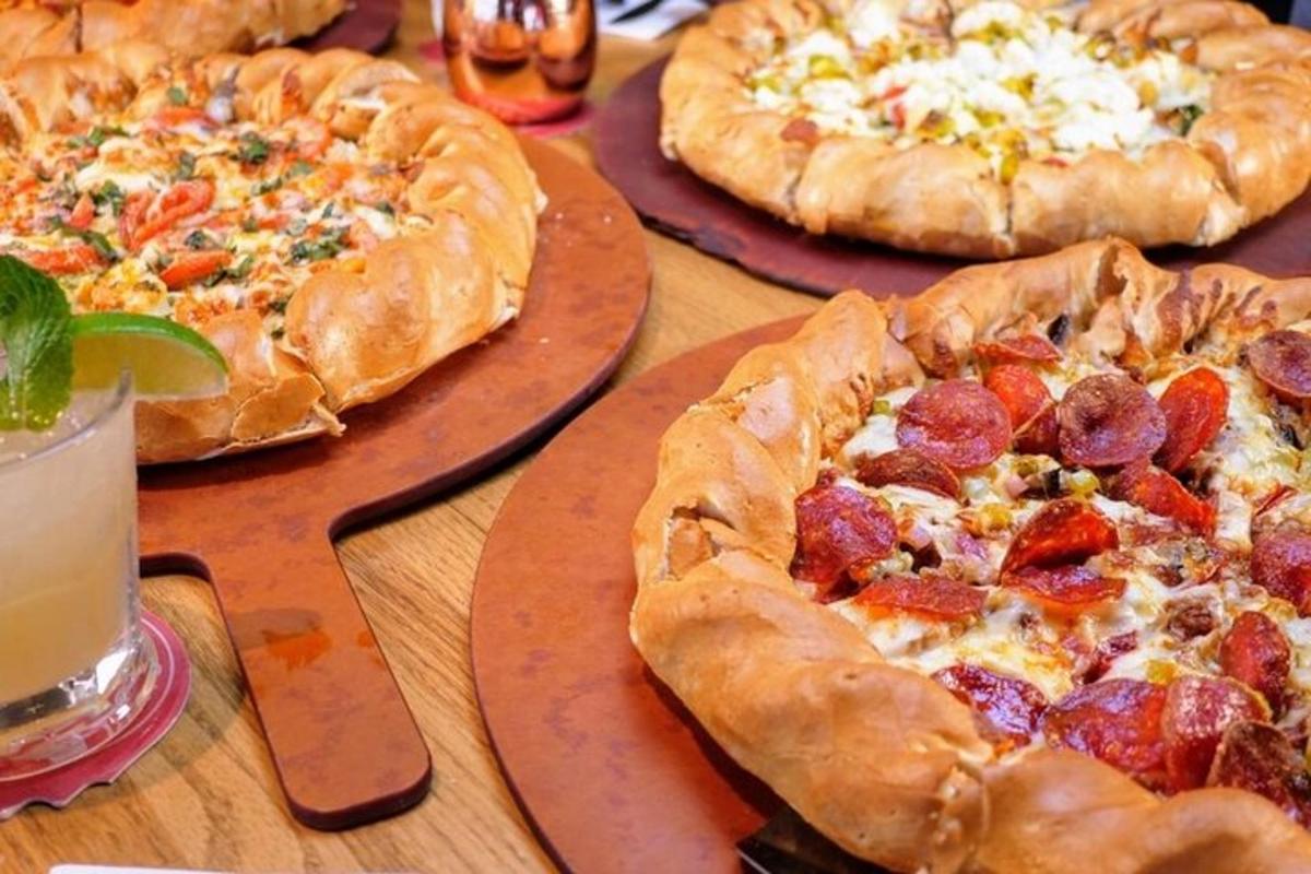 három pizza tányérokon egy faasztalon