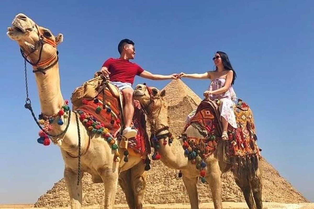 un uomo e una donna a cavallo di cammelli davanti a una piramide
