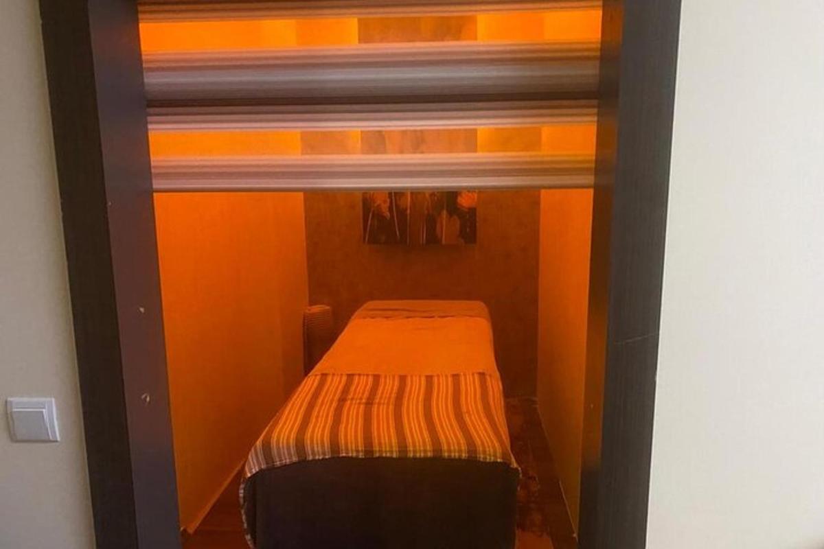 ein kleines Bett in einem kleinen Zimmer mit orangefarbenen Wänden