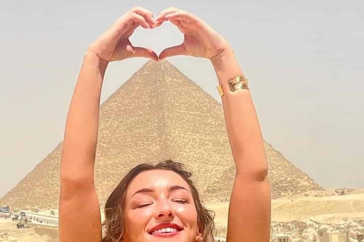 žena robí gesto srdca pred pyramídami