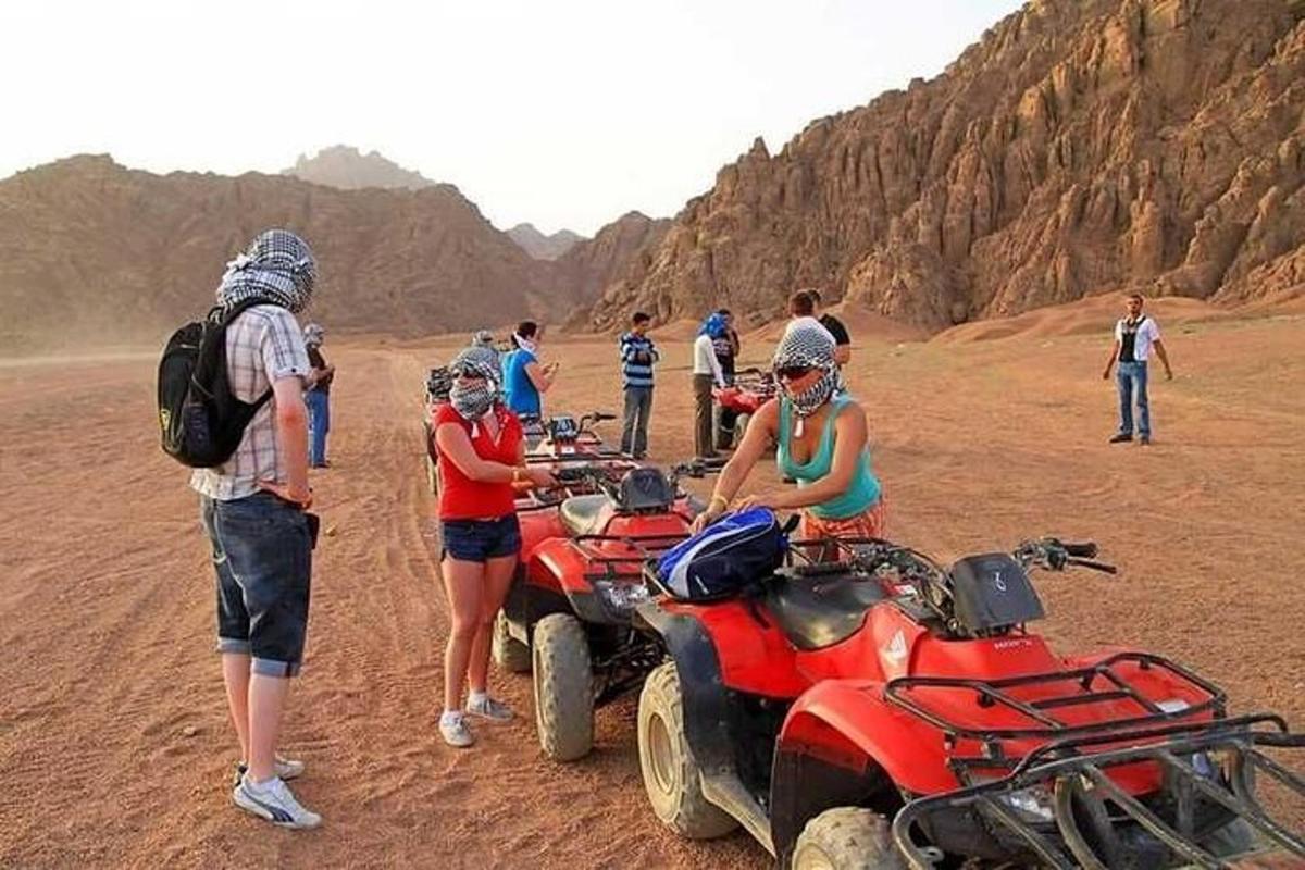 isang grupo ng mga tao na nakatayo sa paligid ng mga atv sa disyerto