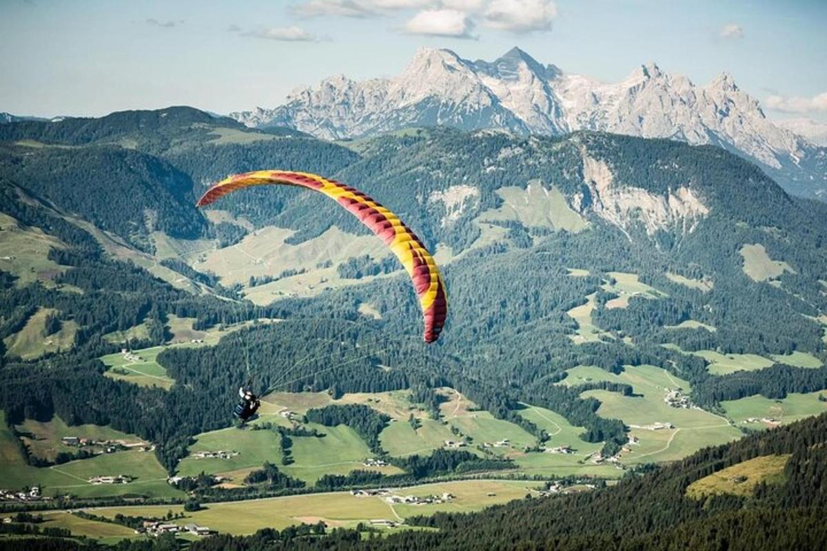 eine Person fliegt mit einem Fallschirm über einen Berg