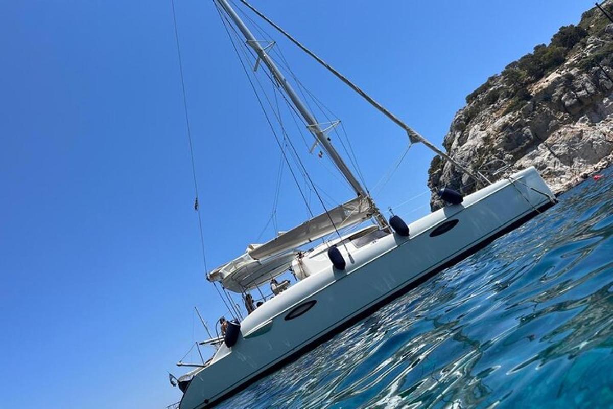 μια βάρκα που επιπλέει στο νερό δίπλα σε έναν απότομο βράχο