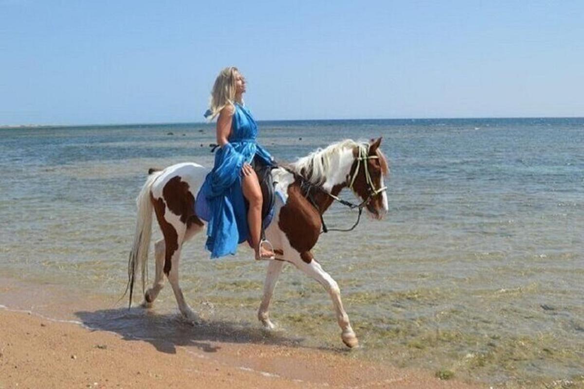 una donna in un vestito blu a cavallo sulla spiaggia