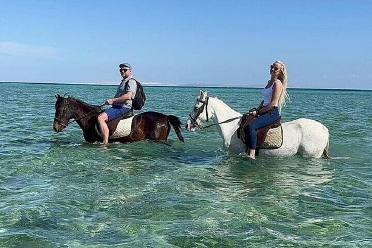muž a žena jedoucí na koních v oceánu