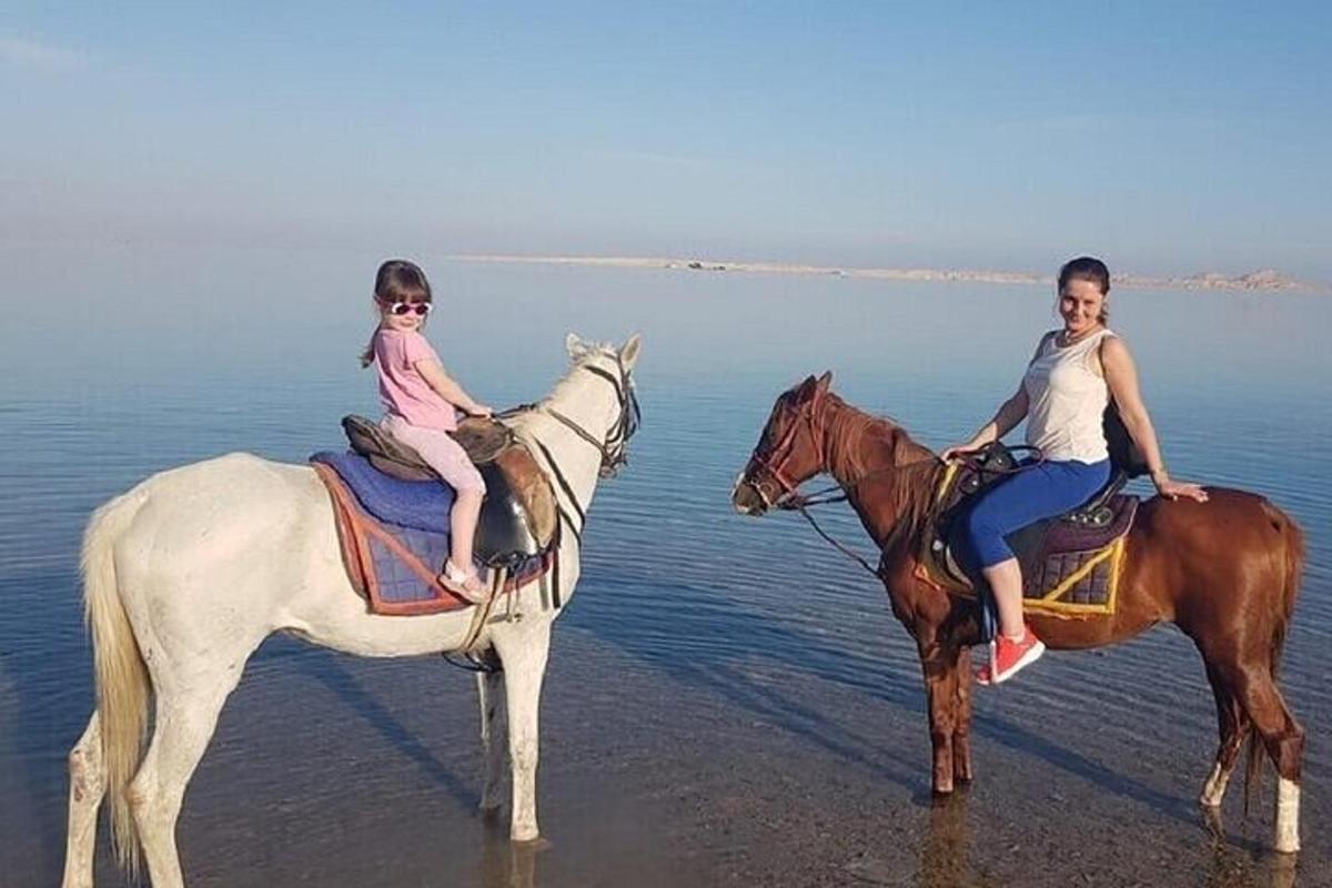 una donna e una ragazza a cavallo sulla spiaggia