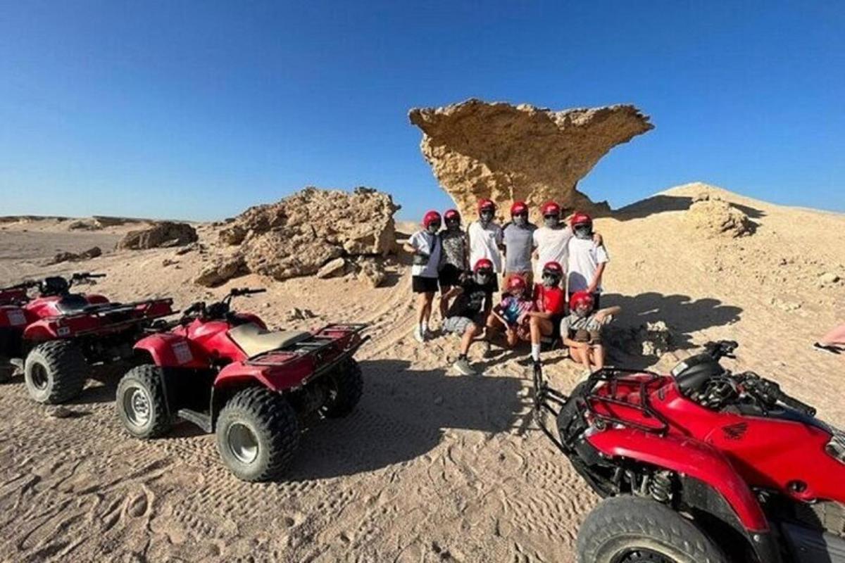 un gruppo di persone in piedi nel deserto con i quad