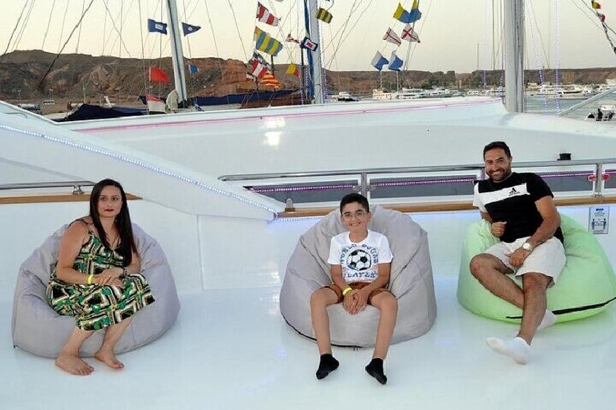 three people sitting on the bow of a boat