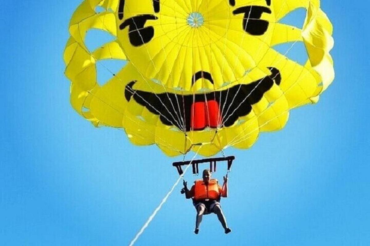 a man flying a large yellow parachute in the sky