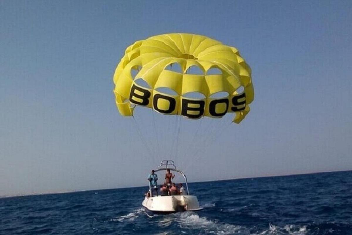 a yellow parachute flying over a boat in the ocean
