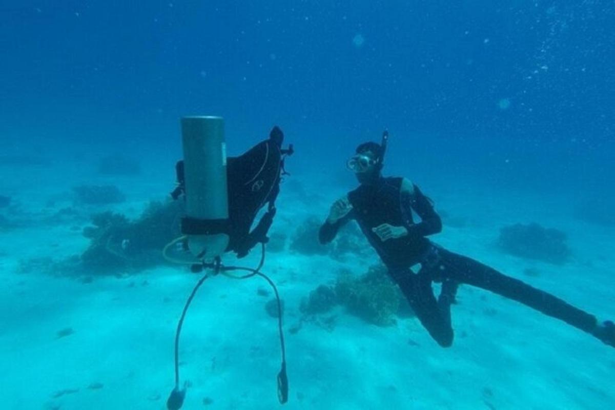 un home està dret a l'oceà al costat d'un dispositiu de busseig