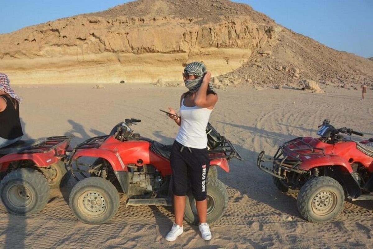 Una mujer parada junto a dos vehículos todo terreno en el desierto.