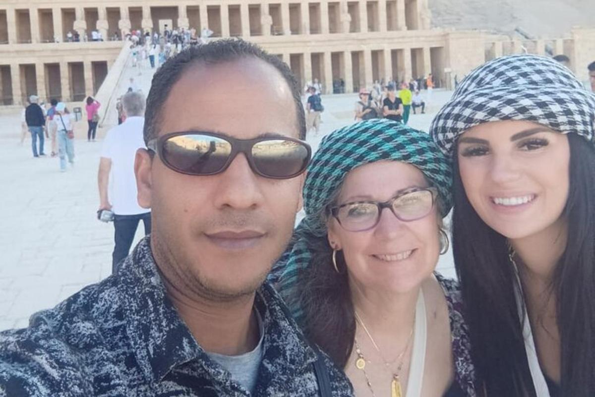 Un hombre y dos mujeres de pie frente a un edificio.