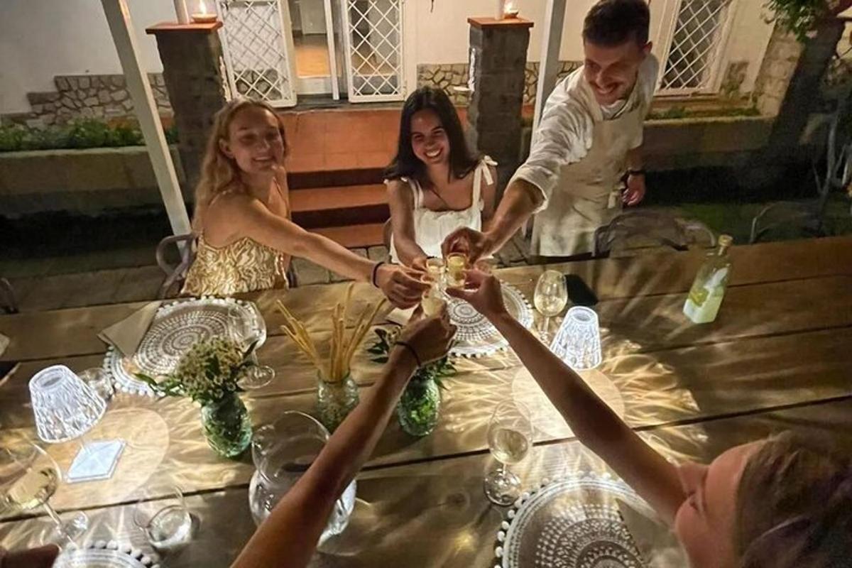 cilvēku grupa, kas sēž ap galdu ar glāzēm