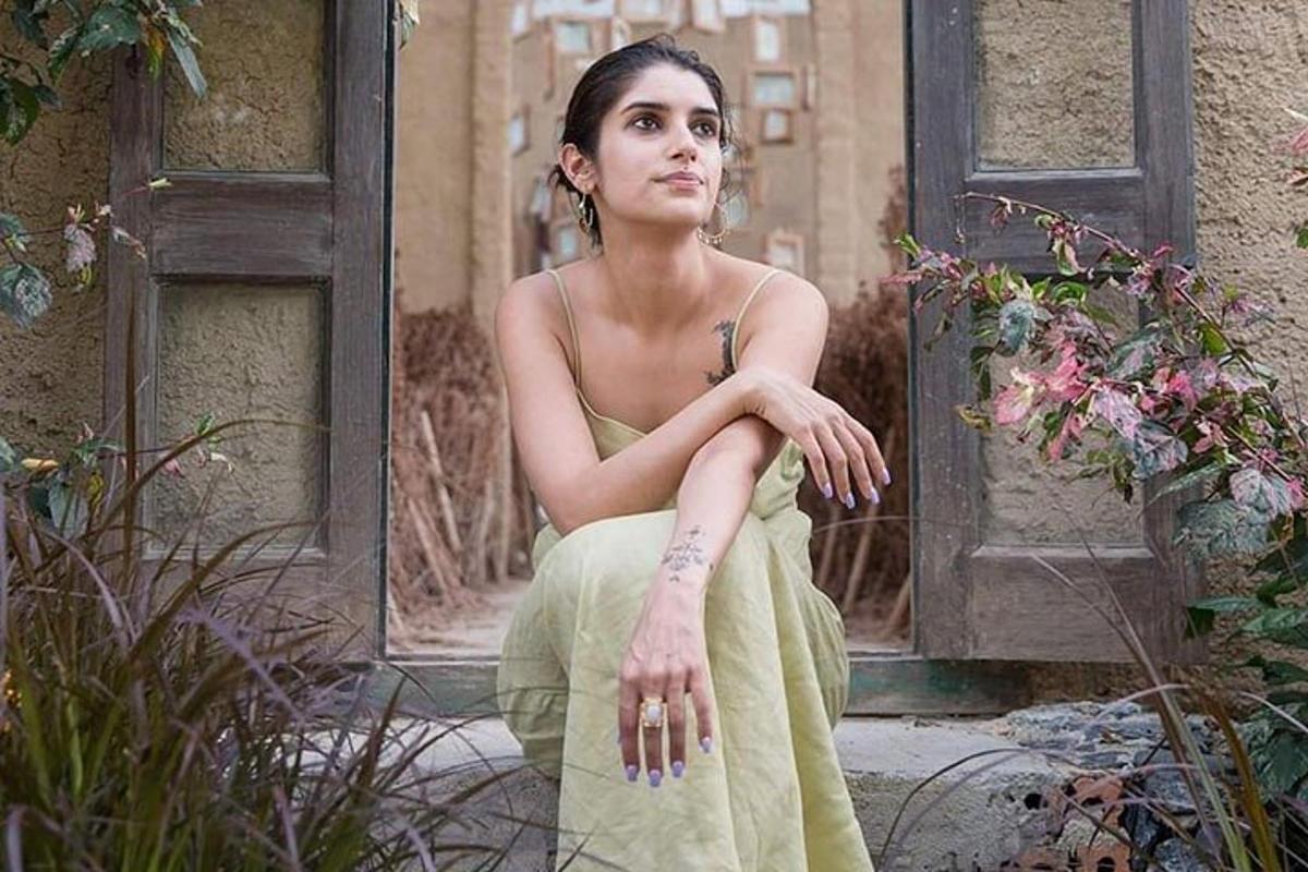 una donna in abito verde seduta davanti a una porta