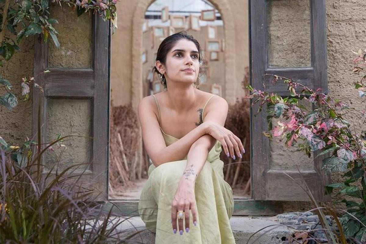 una donna in abito verde seduta davanti a una porta