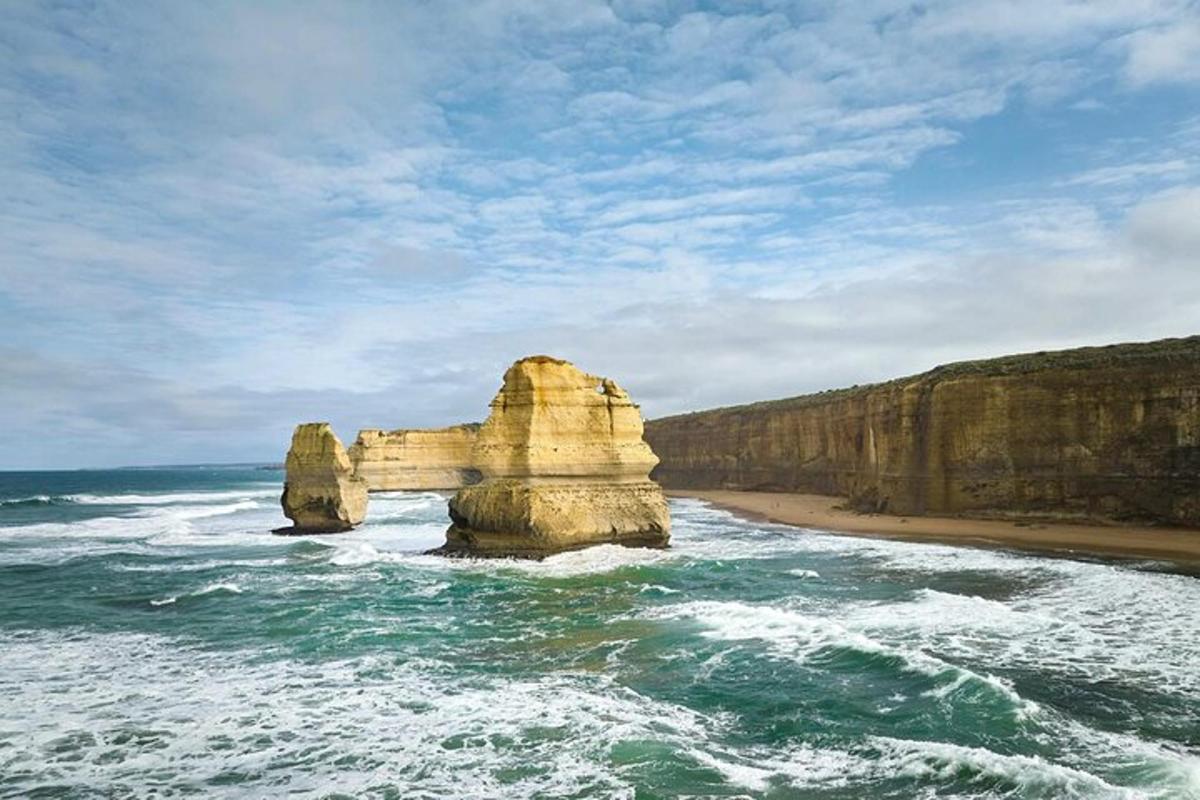 una grande roccia nell'oceano vicino a una spiaggia