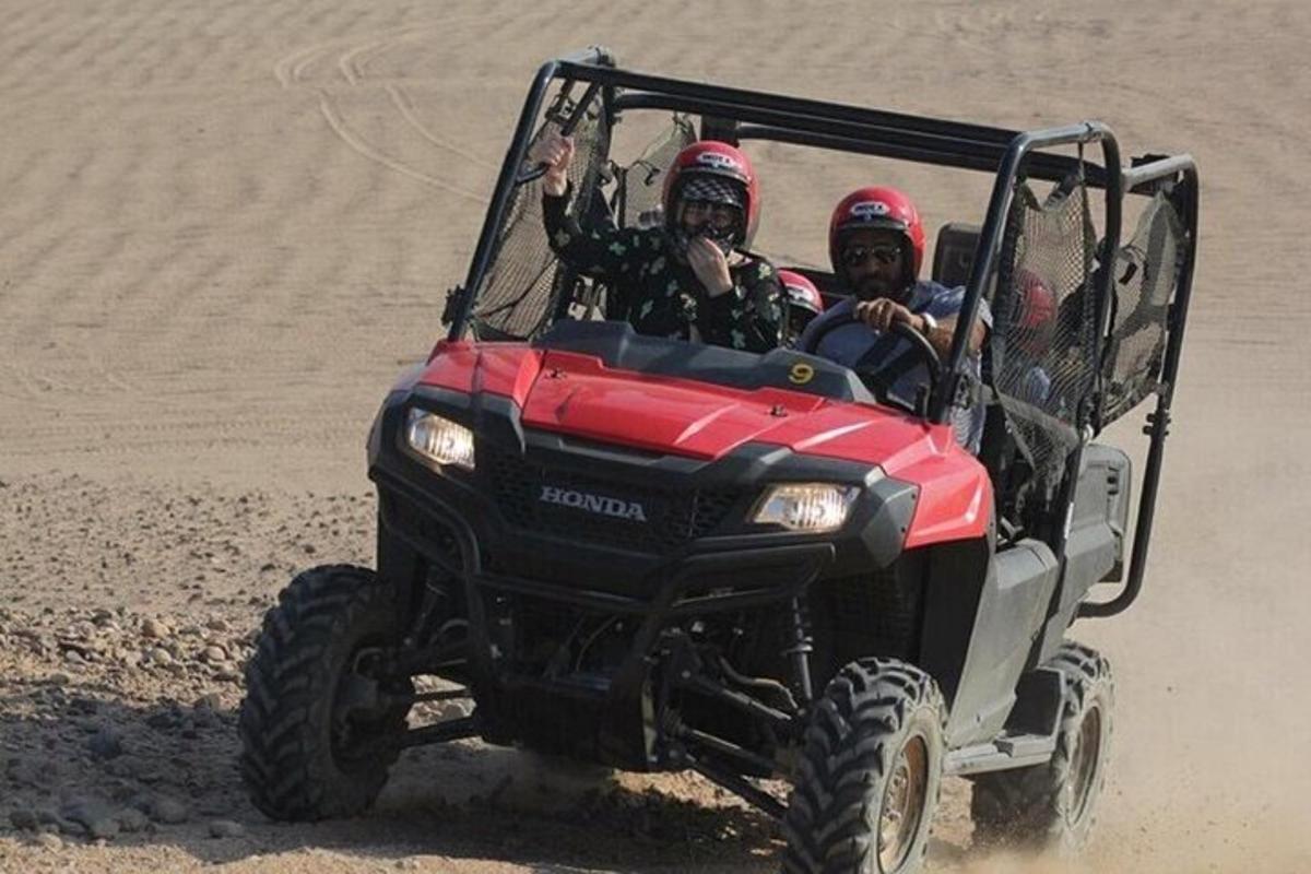 Dos personas viajando en un vehículo de cuatro ruedas en la playa